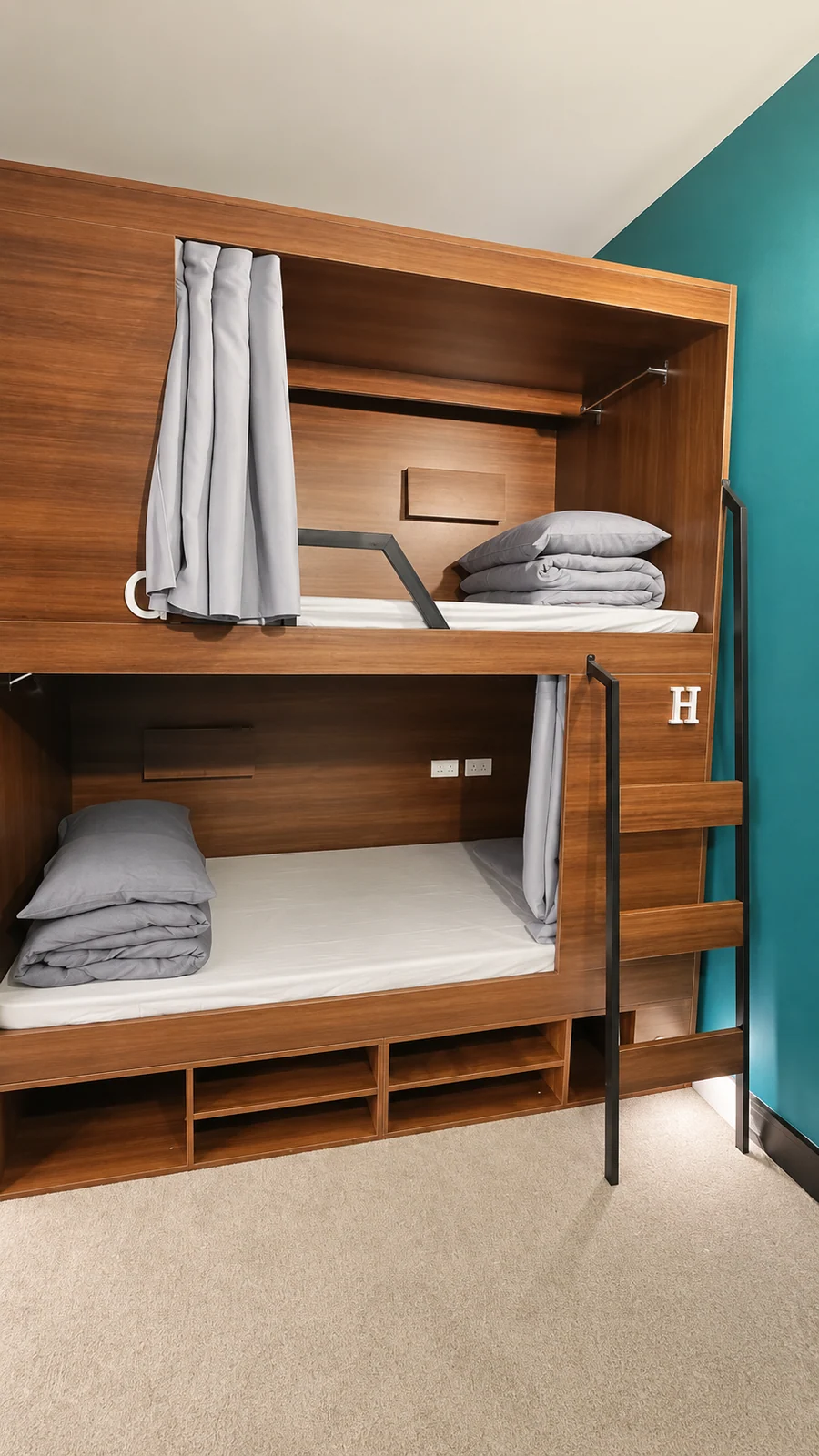 Georgie’s timber pod bunks with grey privacy curtains, bedding and a ladder